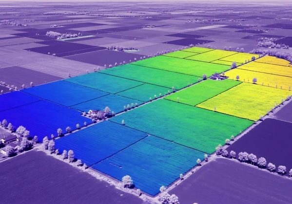 Aerial view of farmland with a digital data overlay showing crop health and yield analysis for precision agriculture